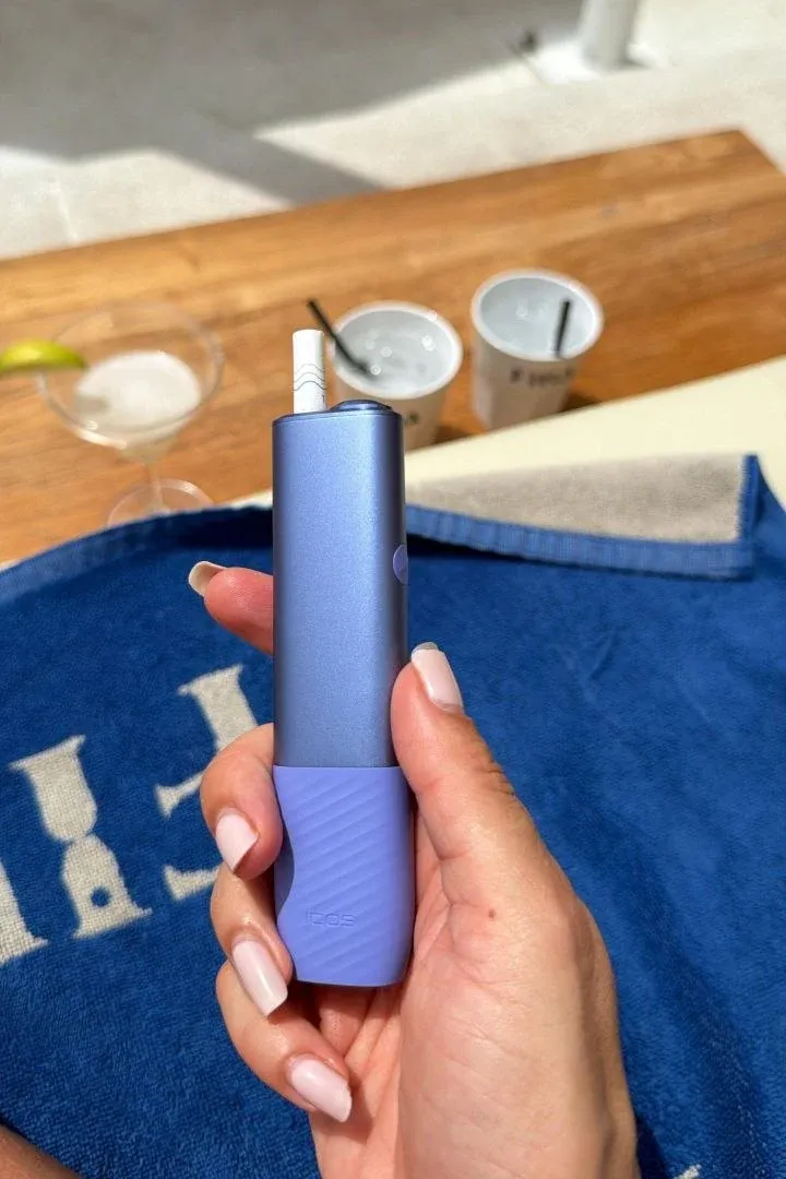 A customer holds a blue ILUMA i by a pool, with drinks on the table behind