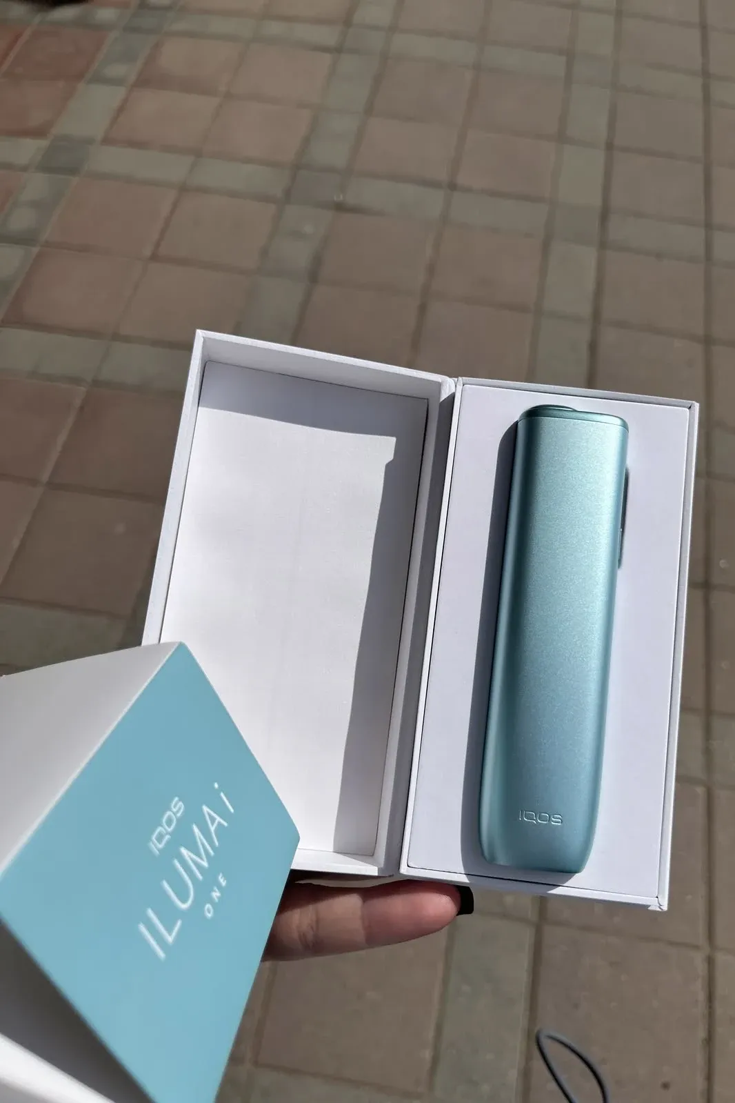 An open ILUMA i ONE box with a turquoise device inside