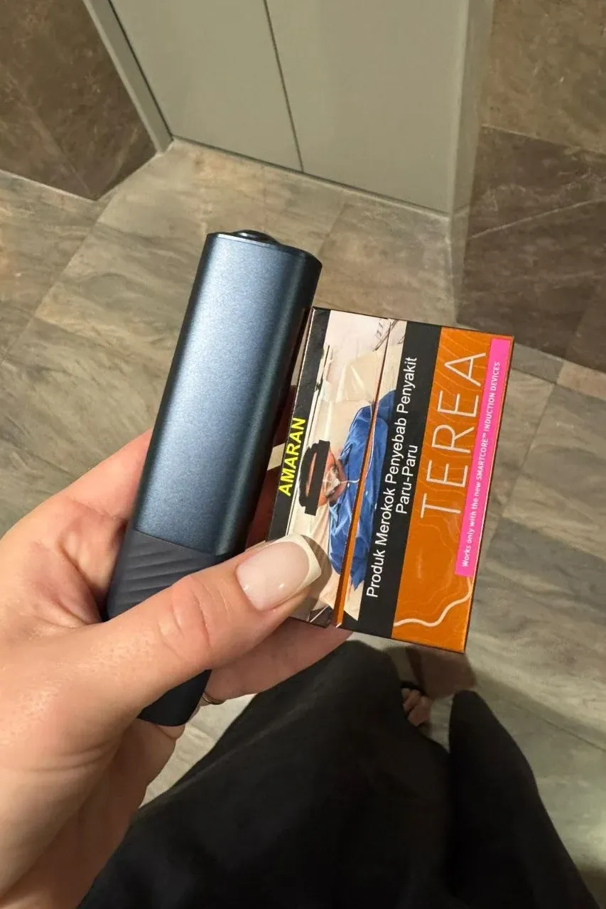 An ILUMA i device and a pack of Malaysian TEREA held by an elevator