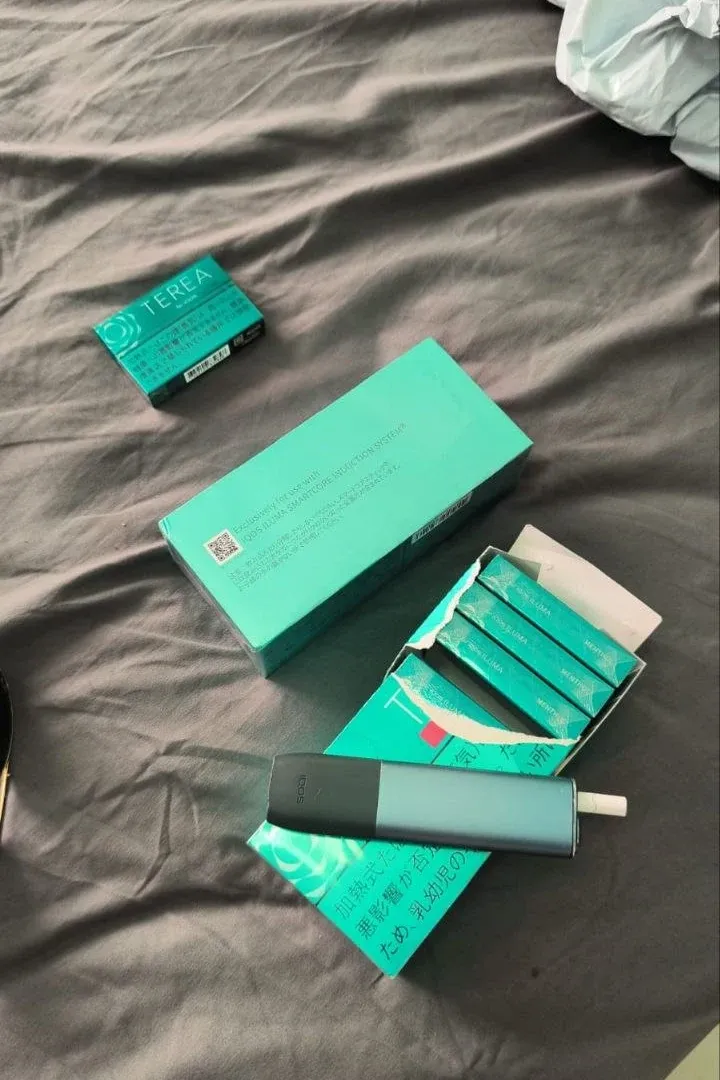 A carton of Japanese TEREA, open packs and an ILUMA i device on a bed